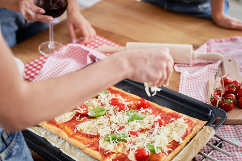 Woman spreading cheese on homemade pizza