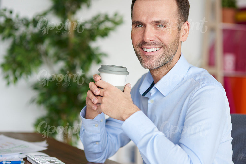 Man with coffee next to the computer