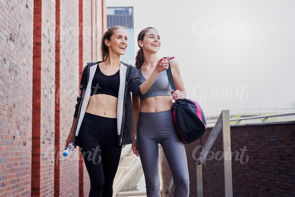Two smiling athletic women in sports clothes pointing their finger