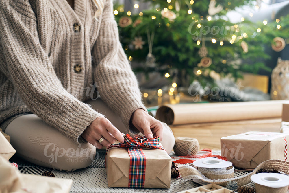 Unrecognizable caucasian woman wrapping Christmas gifts on the floor 