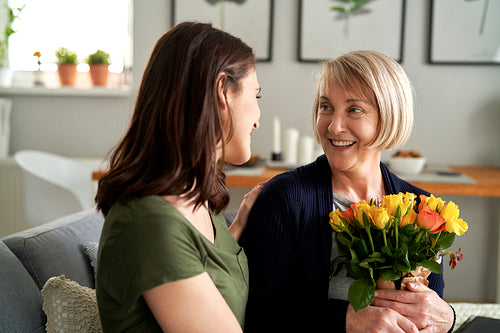 Woman giving mother bouquet of flowers