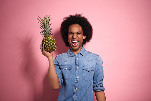 Happiness African man holding a pineapple in a studio shot.