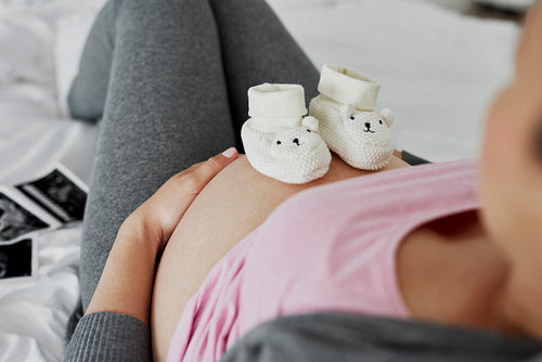 Baby shoes on pregnant abdomen