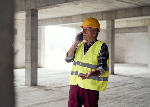 Senior caucasian man talking by mobile phone on the construction site
