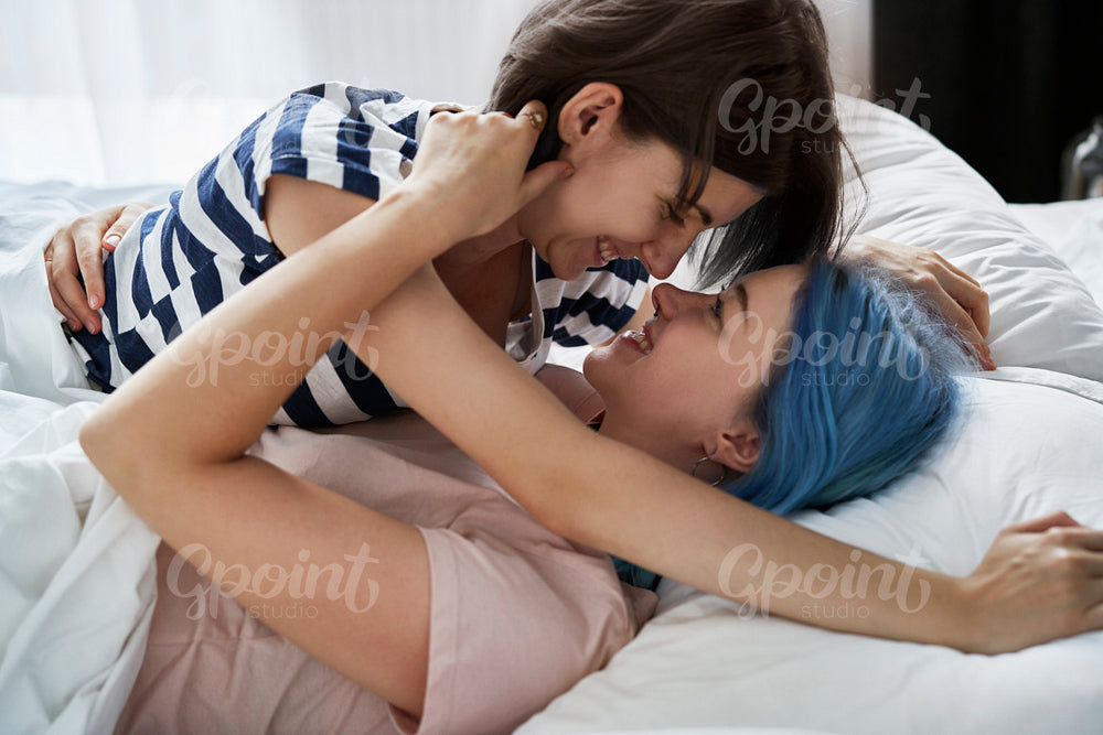 Close up of happy lesbian couple hugging in bed