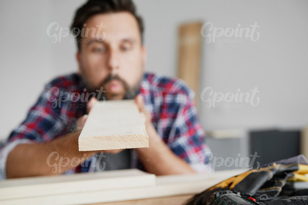 Man blowing dust off a board