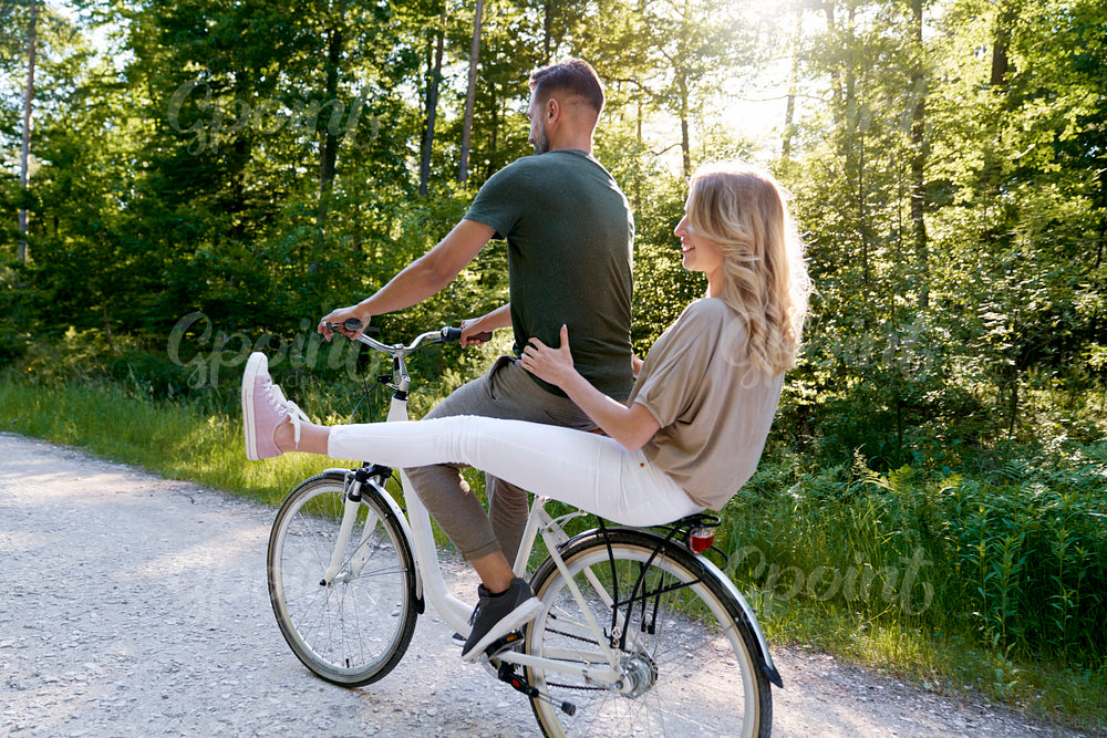 Rear view of couple sharing a bicycle in the forest