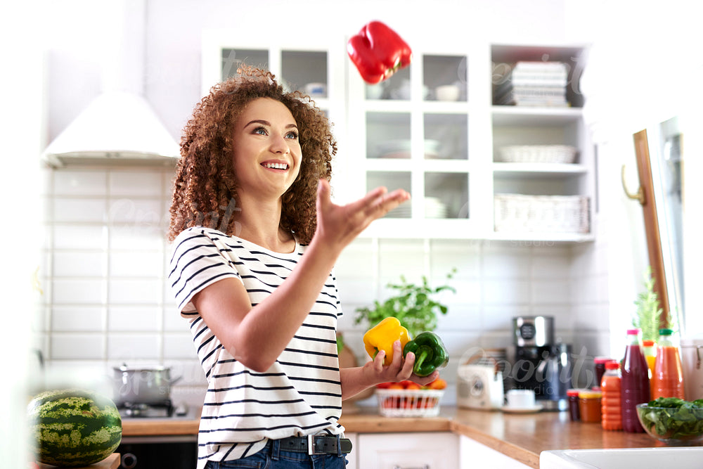 Young woman having fun with pepper in the kitchen