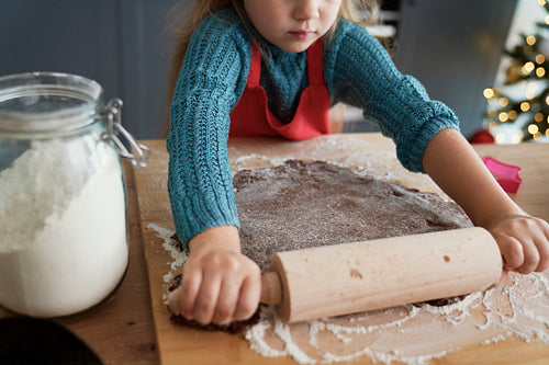 Girl rolling gingerbread pastry for homemade cookies