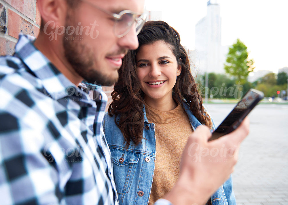 Young woman looking at man with smart phone