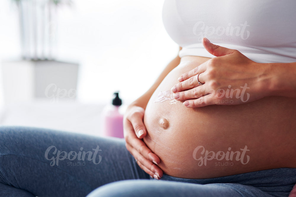 Woman's hand applying moisturizer her belly