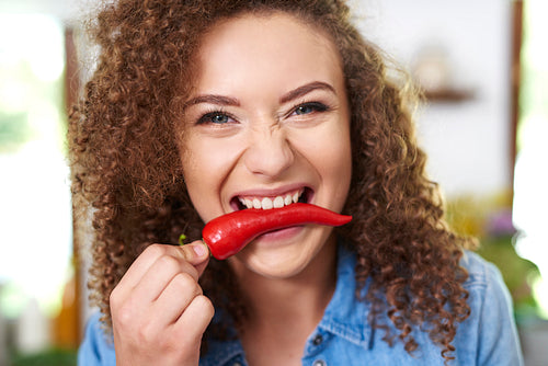 Woman holding red pepper in her mouth