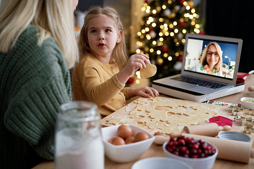 Surprised little girl with Christmas cookies looking at mother