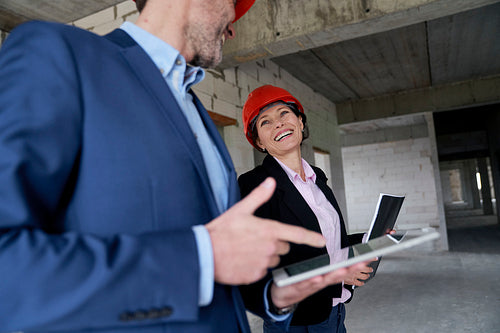 Female caucasian engineer and business woman holding document while standing on construction site