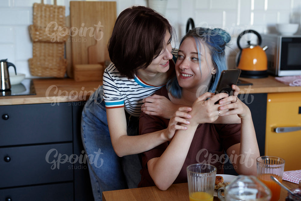 Happy lesbian couple hugging during breakfast
