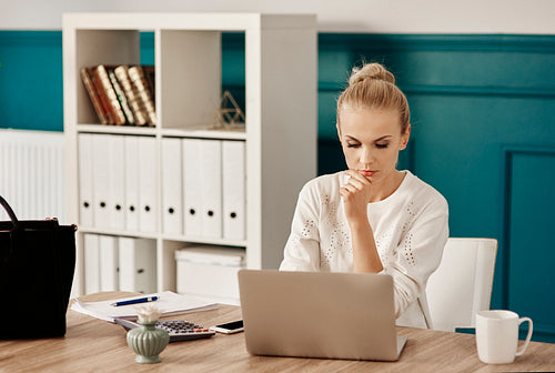 Focused woman using laptop at home office