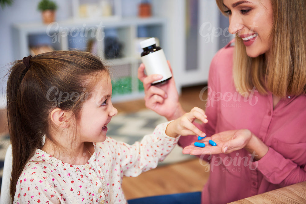 Young mum giving her little daughter the medicine