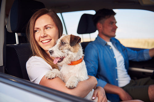 Young couple and their dog traveling together in a car