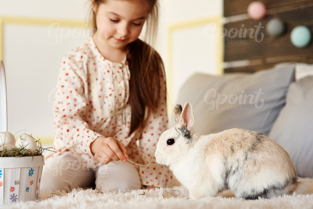 Girl having fun with rabbit on the bed
