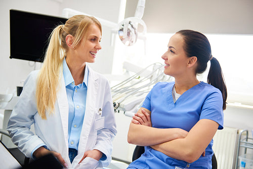 Two smiling, female dentist sitting face to face