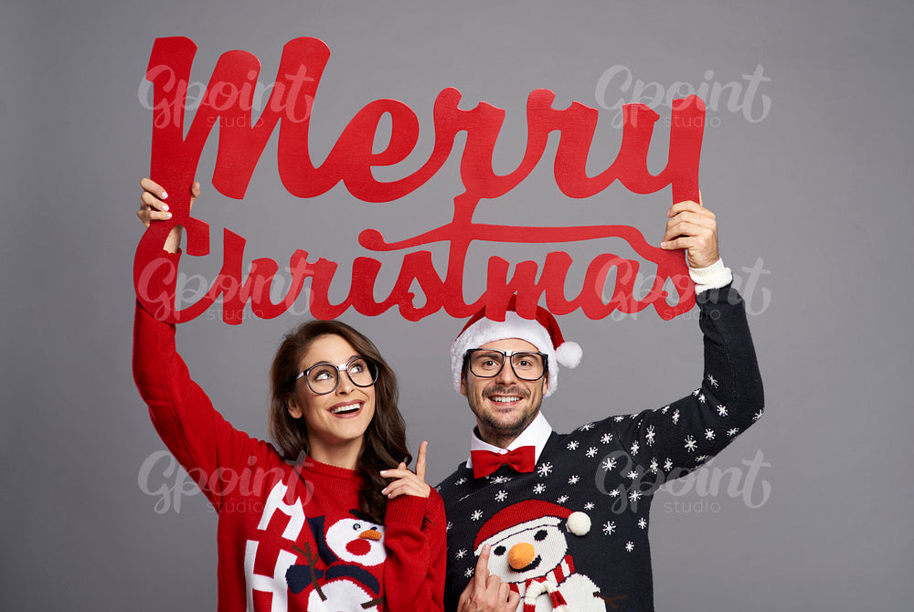 Couple holding a big sign telling Merry Christmas