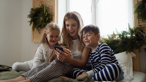Mom and kids using smartphone at Christmas morning