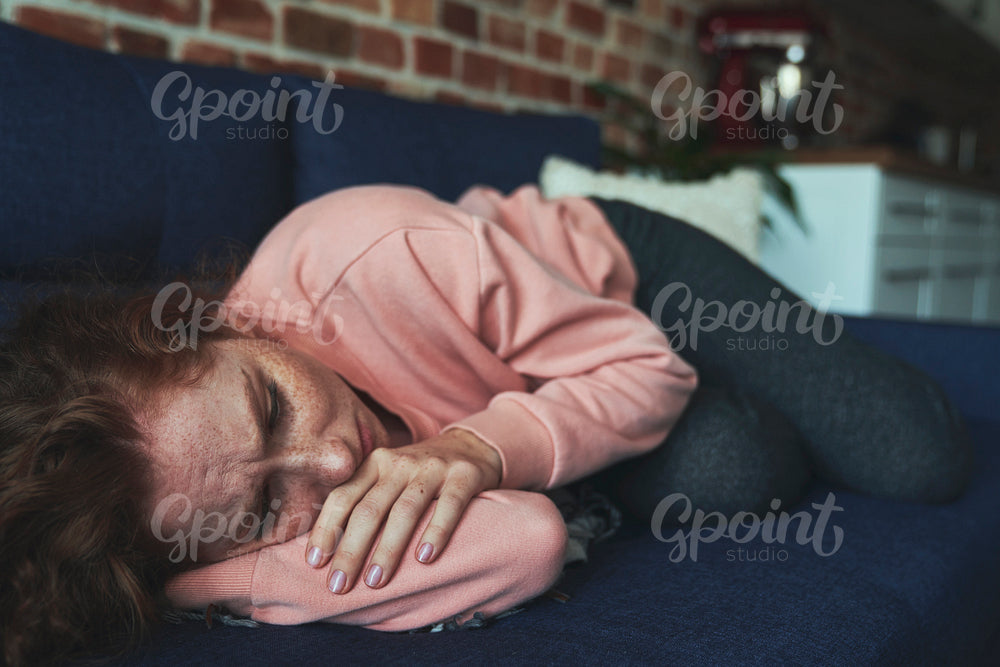 Depressed young caucasian woman lying on sofa