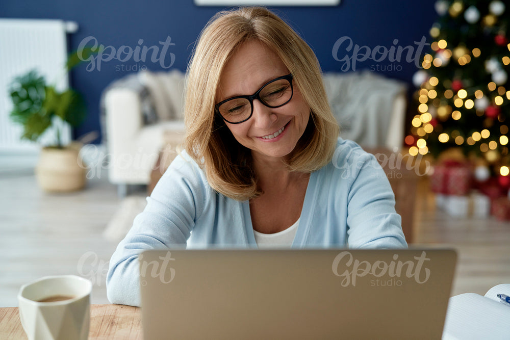Front view of mature woman using laptop during Christmas time