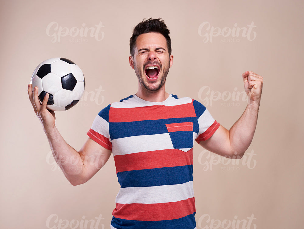 Ecstatic male fan with soccer ball cheering