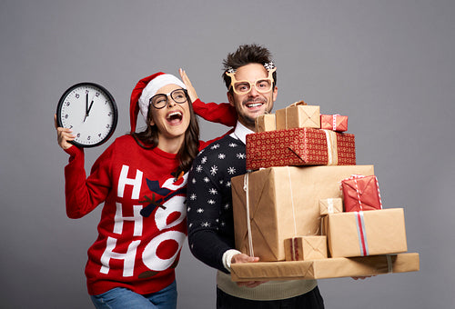 Playful couple holding stack of Christmas gifts