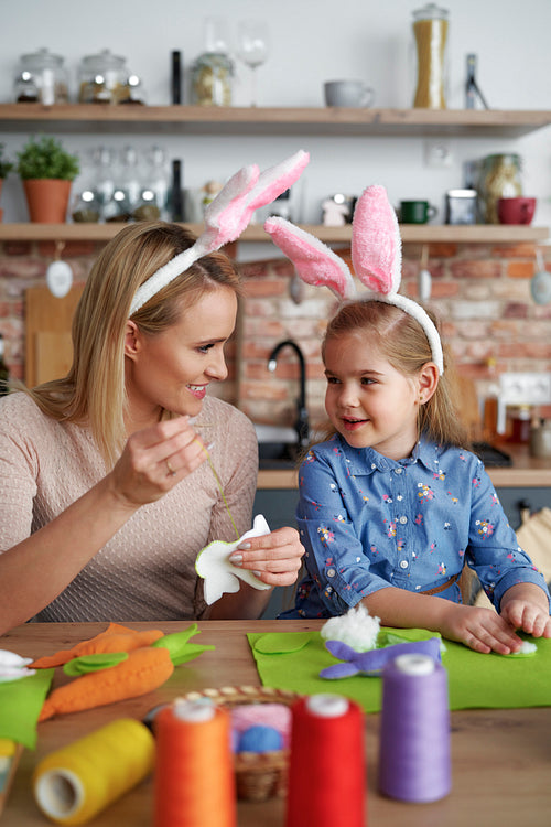 Mother and daughter in rabbit ears sewing Easter toys