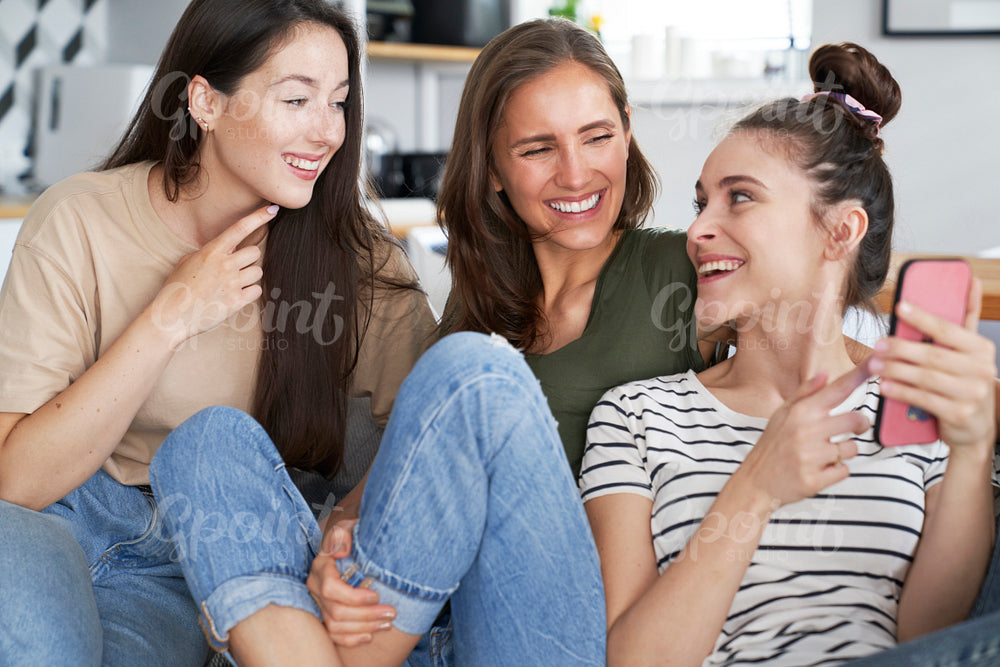 Three friends smiling while browsing smart phone
