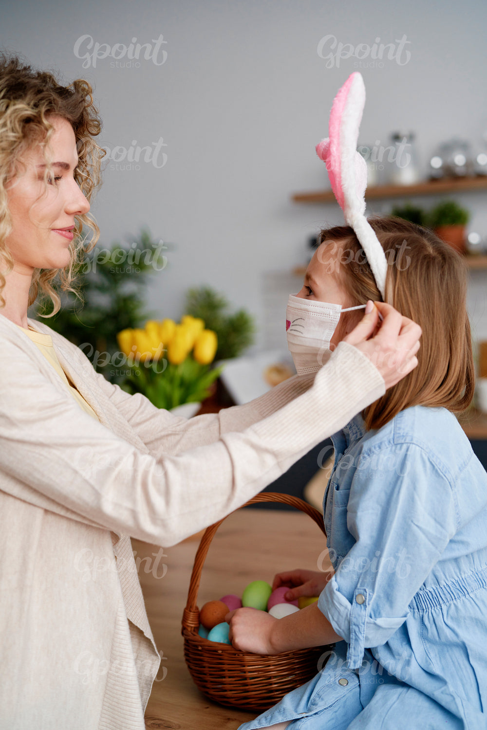 Side view of mother putting on a protective mask for daughter