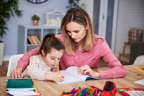 Affectionate mum helping her daughter with difficult homework