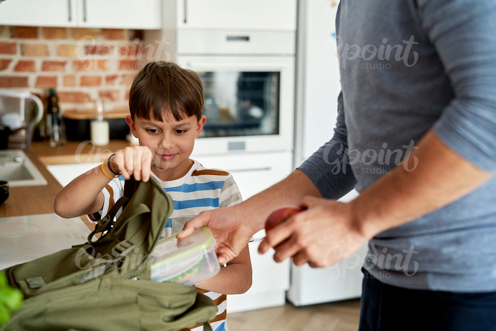 Father packing healthy food lunch boxes for son