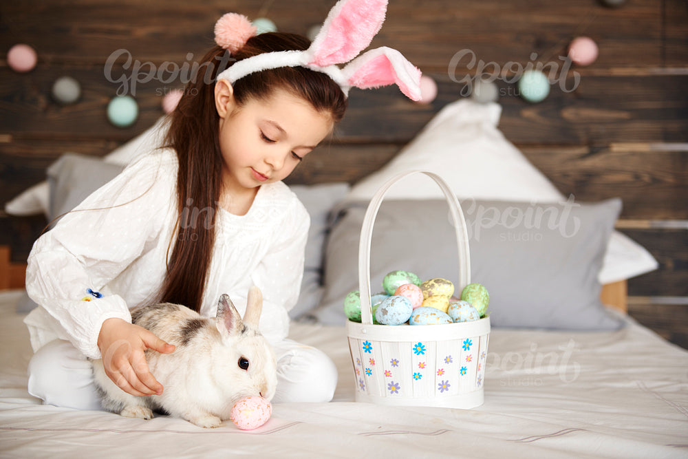 Girl playing with rabbit in bedroom