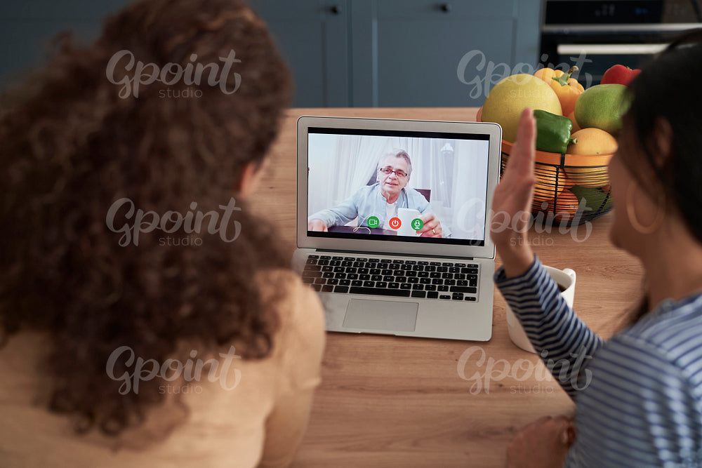 Rear view of women during videoconference with an old man