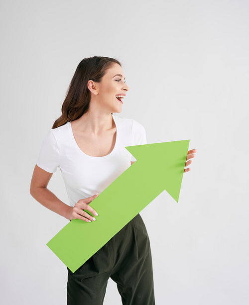 Excited woman holding rising arrow in studio shot