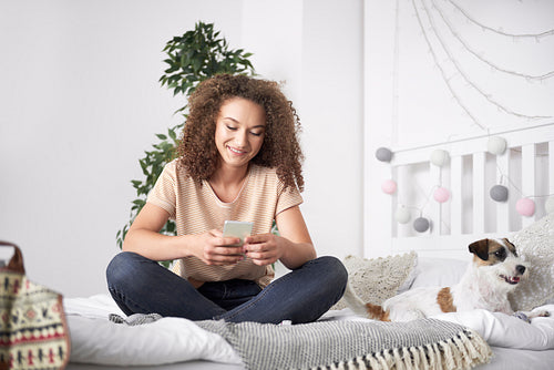 Teenage girl using mobile phone in her bedroom