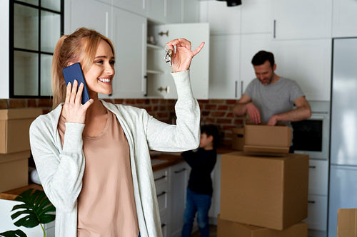 Happy woman calling and holding keys to a new house