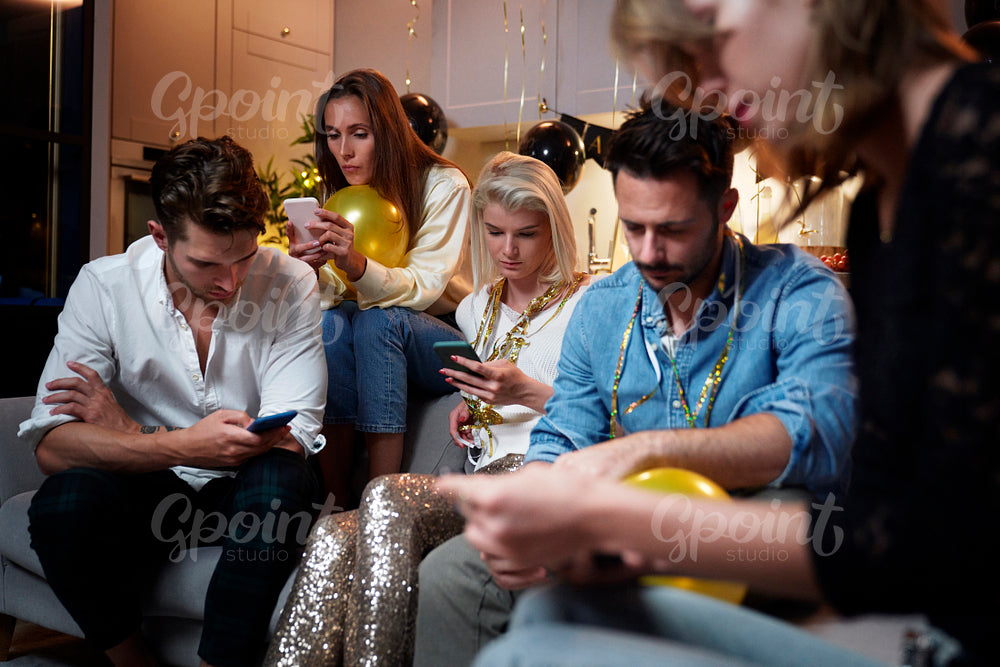 Friends focused on mobile phones on party