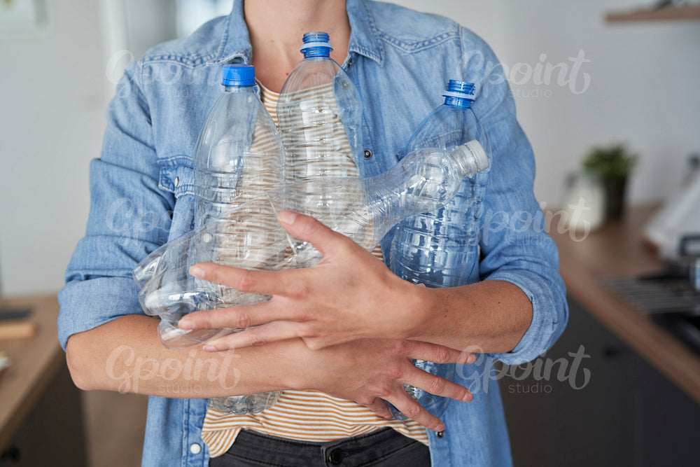 Woman carrying a lot of empty plastic bottles for recycling