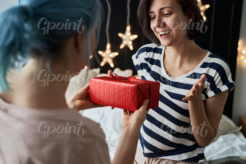 Happy lesbian couple giving Christmas presents in the morning