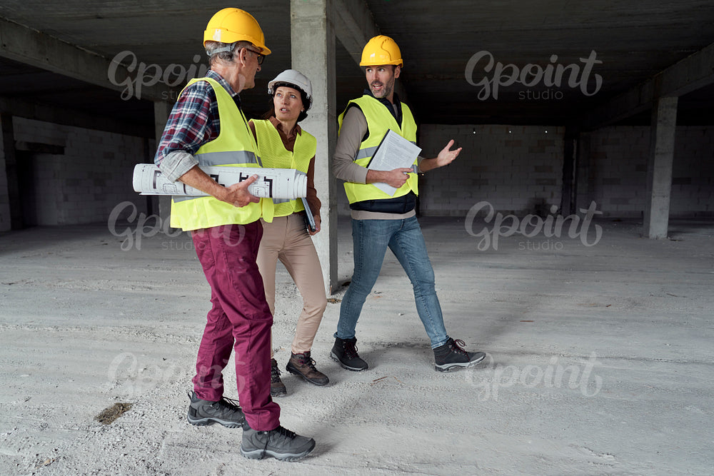 Three busy caucasian engineers walking across the construction site