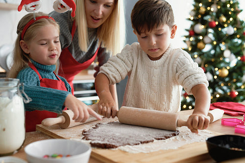 Siblings rolling a gingerbread pastry