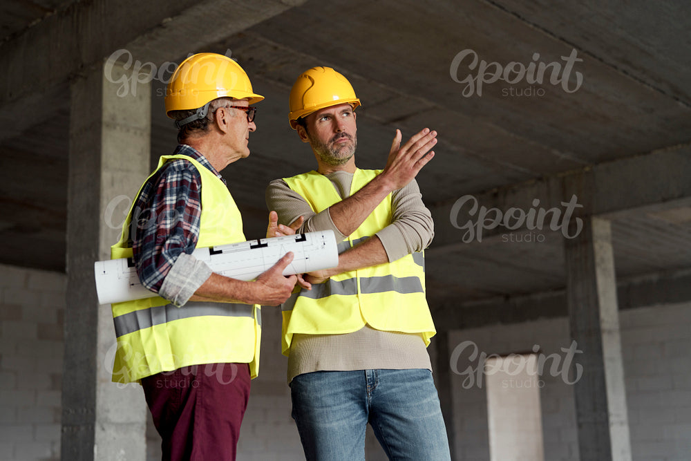 Two caucasian engineers discussing on construction site  