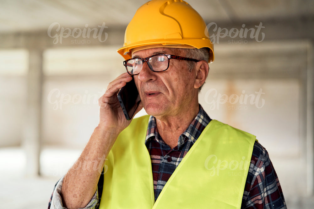 Caucasian senior engineer talking on mobile phone on construction site