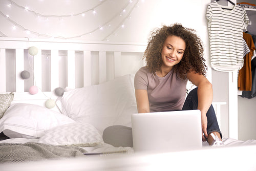 Teenage girl using a laptop in her bedroom