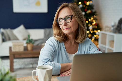 Mature woman sitting and thinking in front of laptop