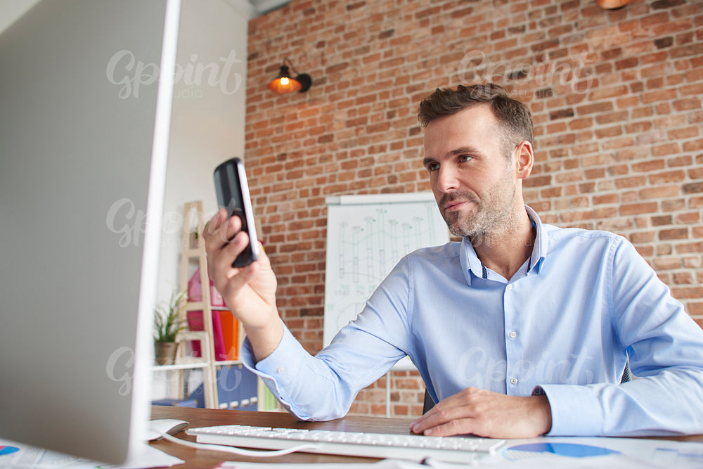 Man with phone in front of computer